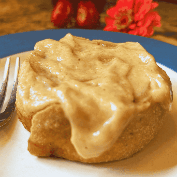 iced pumpkin cinnamon roll on a plate with a fork