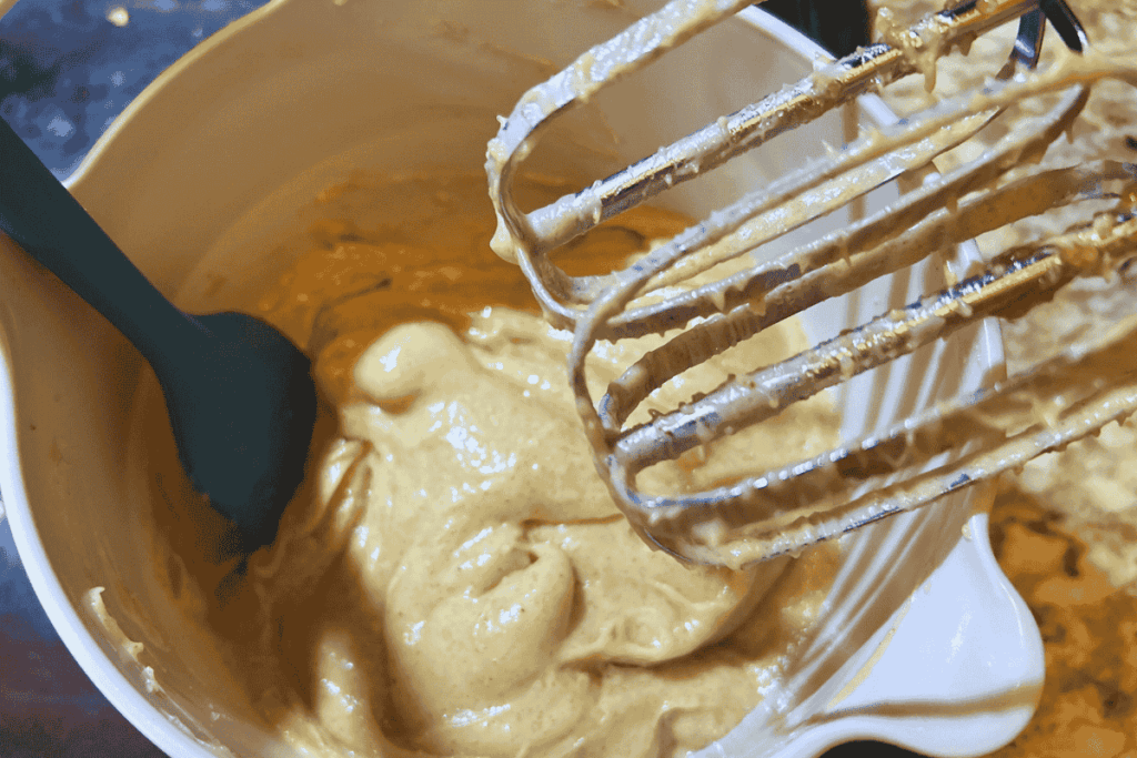 mixing cream cheese with melted butter and brown sugar using hand mixer