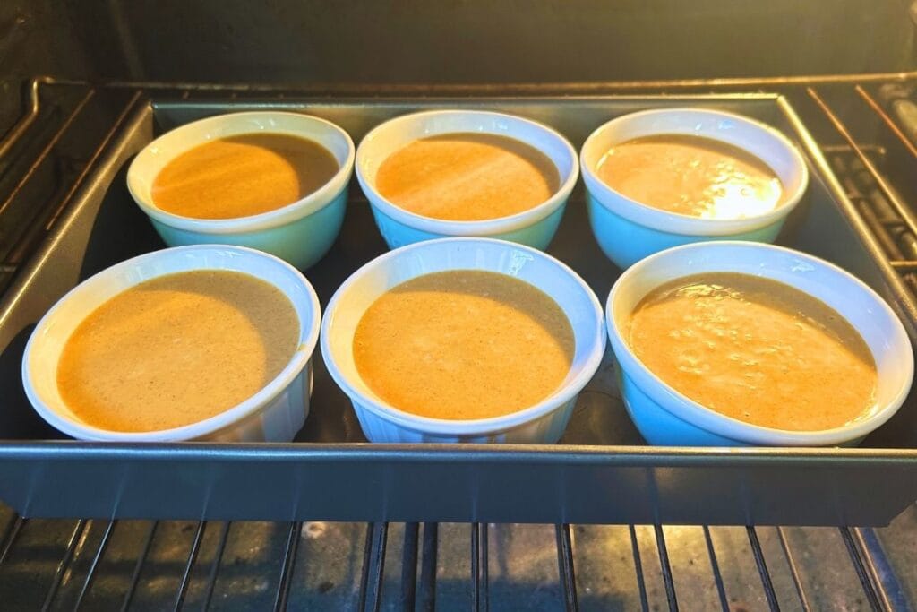 orange base in ramekins going into the oven to bake