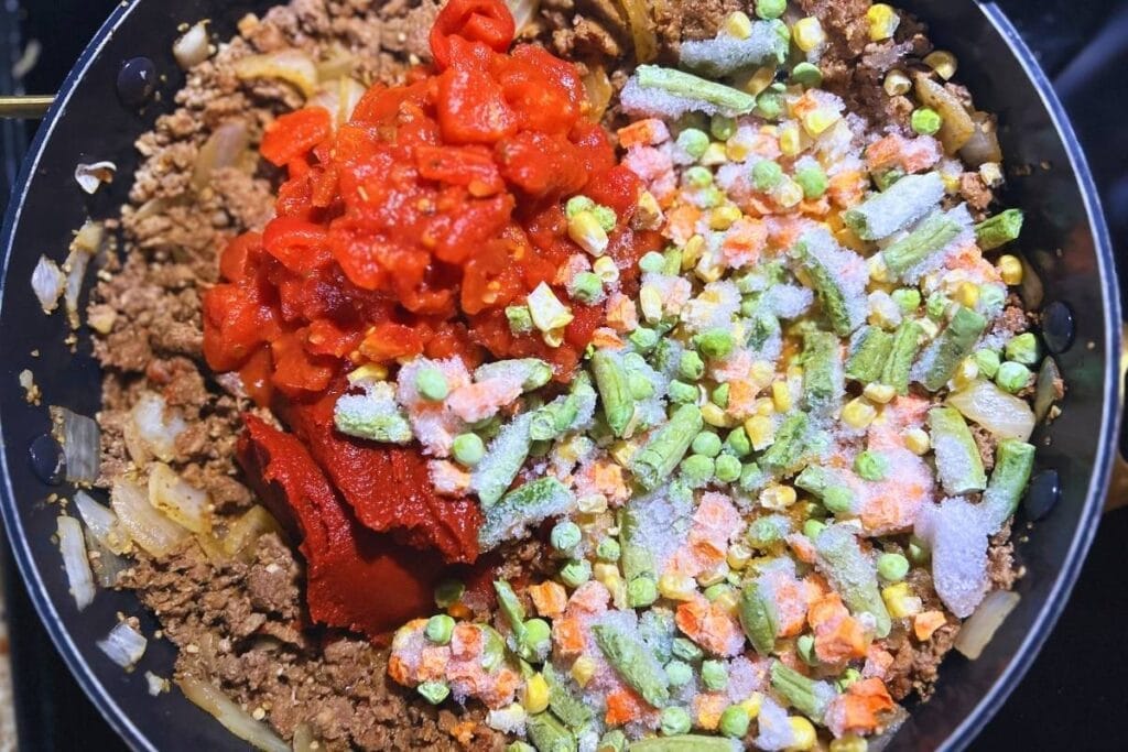 tomatoes and frozen vegetables added to cooked meat