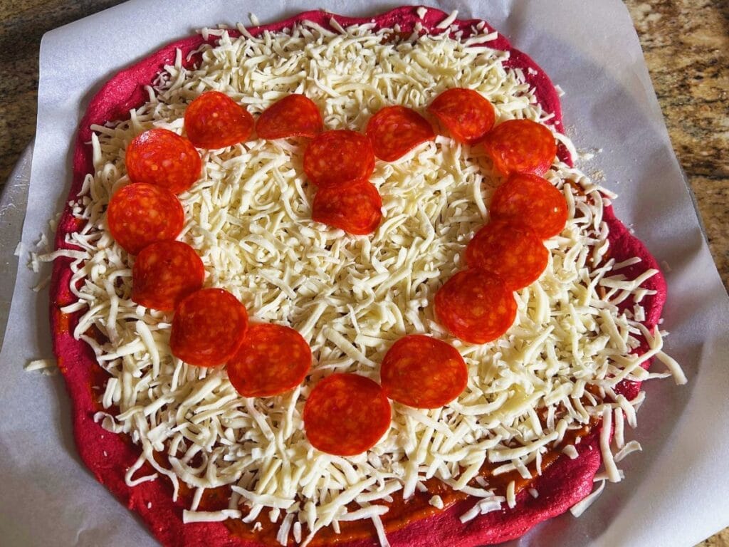 beet pizza topped with a heart made of pepperoni