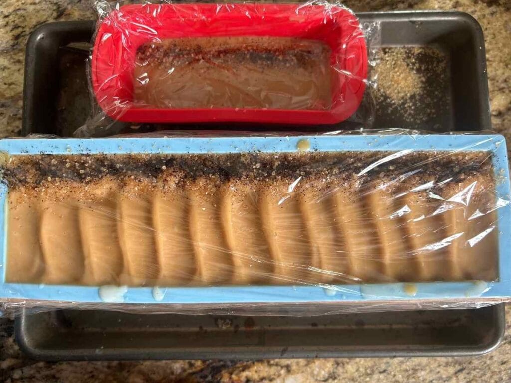 plastic wrap covering soap batter in the molds