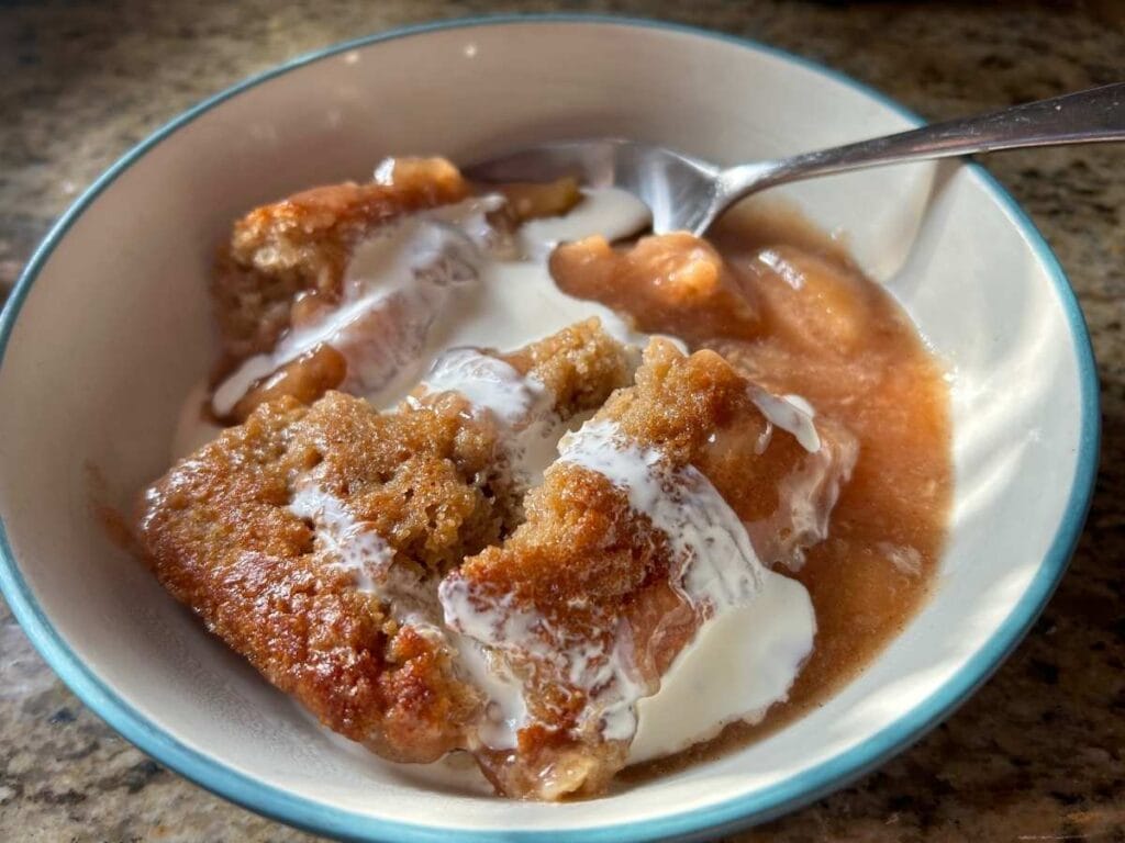 a serving of sourdough apple pie cobbler in a bowl topped with cream