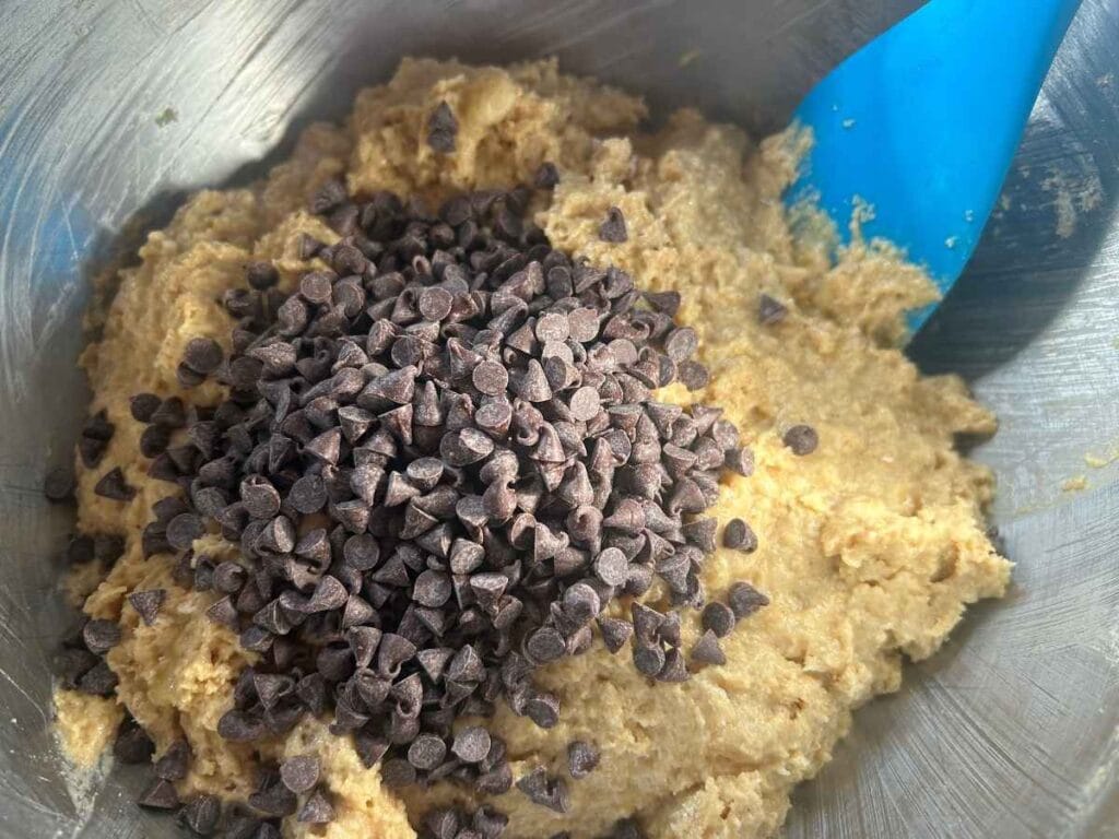 miniature chocolate chips being folded into sourdough banana muffin batter