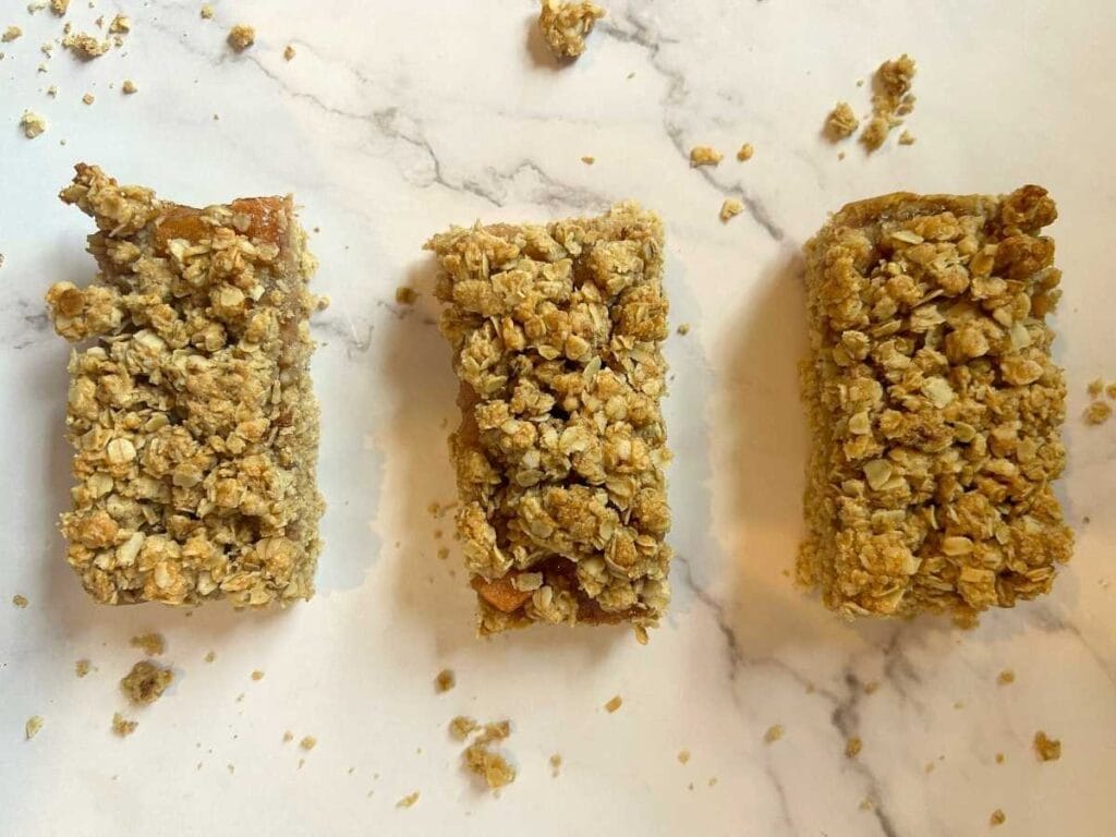 three slices of apple pie oat bars on a white counter